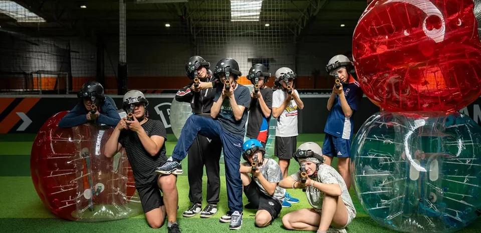 Groupe d’adolescents équipé pour un Laser Game entre des bulles de Bubble Foot