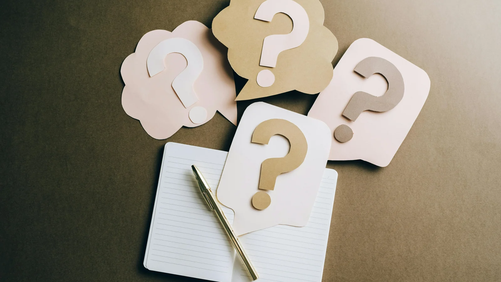 Des points d’interrogation en papier autour d’un carnet illustrent la préparation d’un quiz